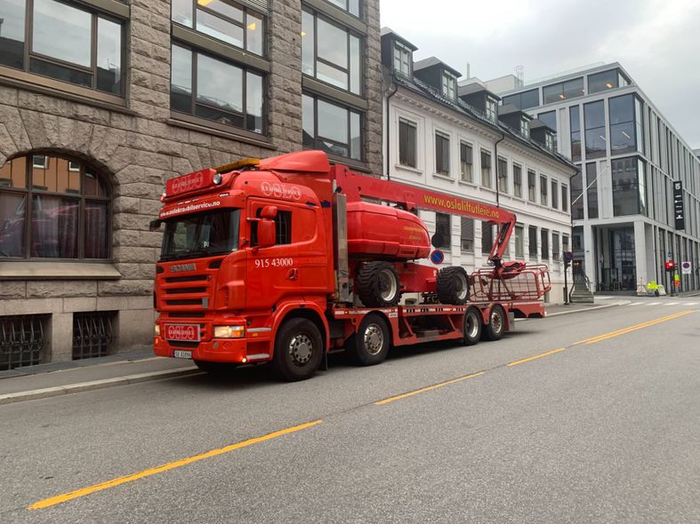 Rød laste- og kranbil som står i en gate