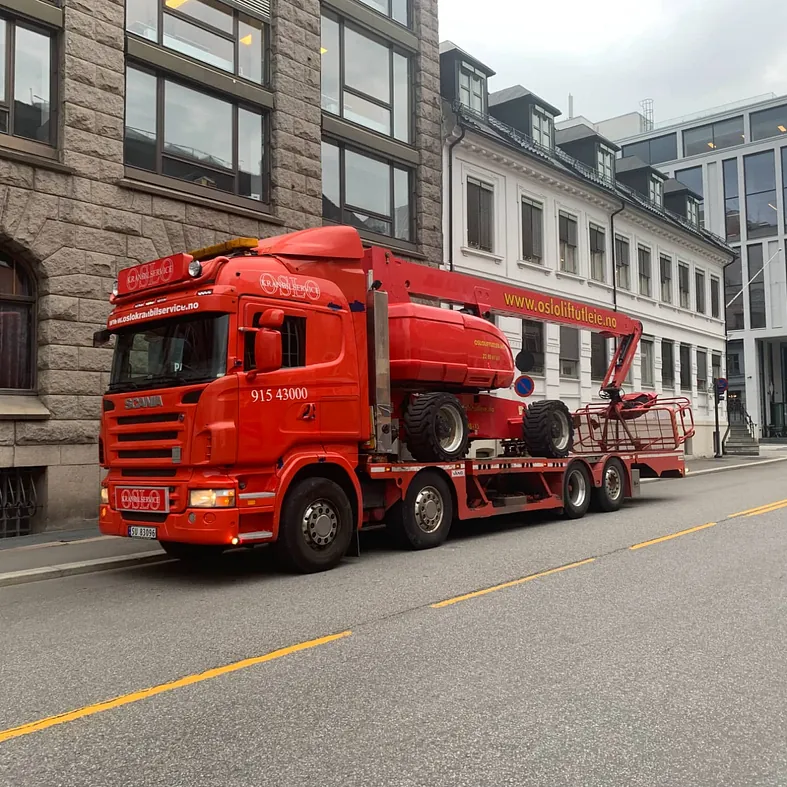 Rød laste- og kranbil som står i en gate