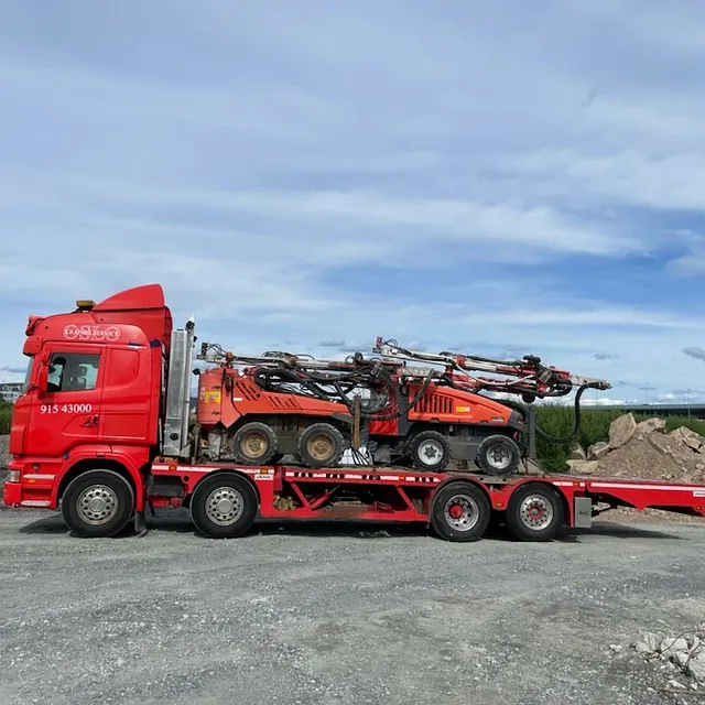 Rød lastebil utfører maskintransport